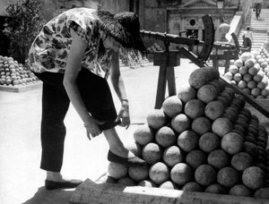 Une femme ajuste le revers de son pantalon en posant son pied sur une pile de boulets de canon dans l