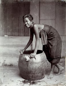 Jeune femme thaïlandaise souriante, poussant un grand conteneur - Unknown photographer