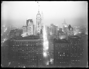 Vue nocturne brumeuse en plongée du bas de Manhattan vers le nord, avec le Singer Building, le Woolworth Building et le Municipal Building visibles, vers 1913 - William Davis Hassler