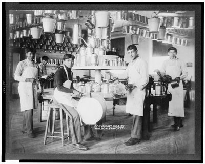 Jeunes hommes amérindiens dans un atelier de métallurgie avec des seaux, des bassines, des arrosoirs et d