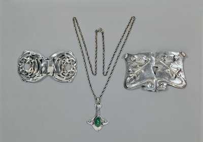 Bijoux en argent conçus pour Liberty. De gauche à droite : Fermoir de taille avec design celtique entrelacé, 1904. Pendentif et chaîne sertis de chrysoprase cabochon. Fermoir de taille avec design repoussé sur martelé - Archibald Knox