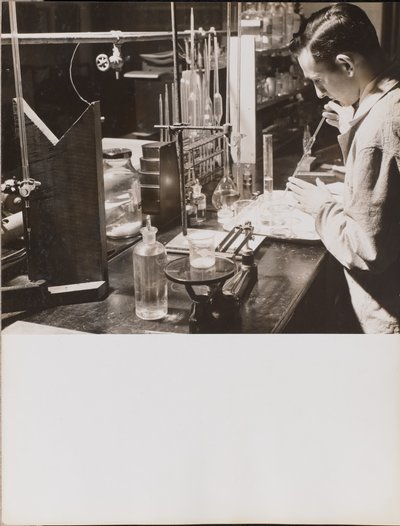 [Un homme dans un laboratoire utilise ses deux mains pour placer une grande pipette dans un bécher]. - Arnold Eagle