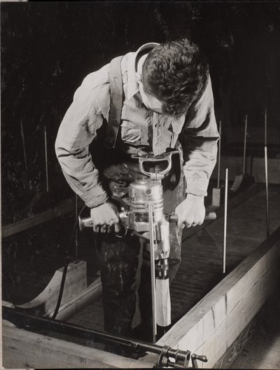 [Un homme utilise une machine portative pour travailler un morceau de bois]. - Arnold Eagle