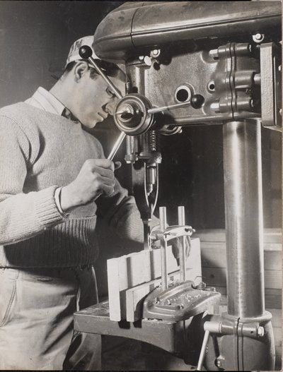 [Un homme utilise une machine pour percer des trous dans deux blocs de bois]. - Arnold Eagle