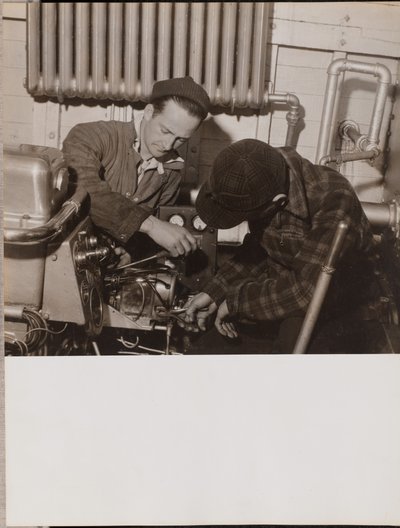 [Deux hommes travaillent sur une machine à l