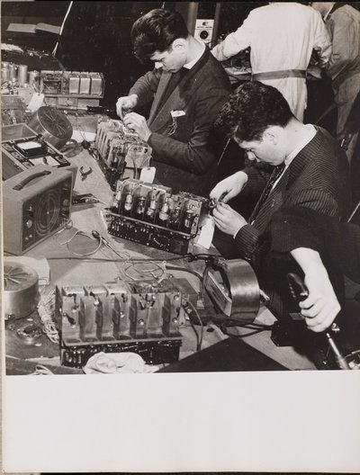 [Deux jeunes hommes portant des blazers travaillent sur des radios]. - Arnold Eagle