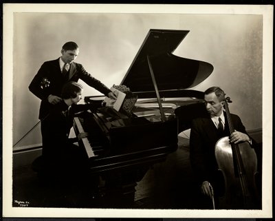 Femme aveugle, Miss Harding, au piano instruisant deux hommes aveugles au violon et au violoncelle, 1936 - Byron Company