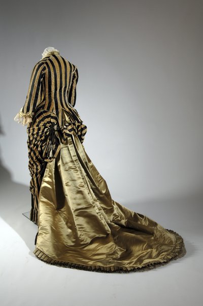 Robe de soirée, vers 1884 (vue oblique arrière). Satin de soie et velours coupé, dentelle, glands et franges en fil de soie. Charles Frederick Worth, France. - Charles Frederick Worth