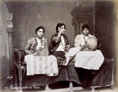 Portrait de trois jeunes chanteurs arabes en tenue ethnique avec de longs colliers. Ils posent dans le studio, assis. Deux d