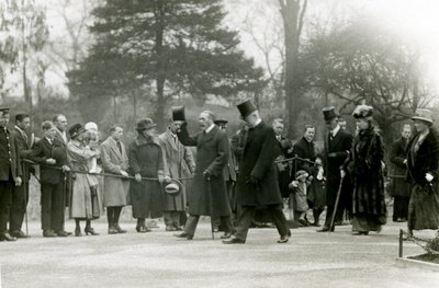 Le roi George V, levant son chapeau à la foule devant son entourage, lors d