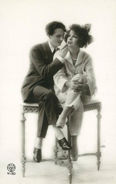 Homme androgyne en costume appliquant du rouge à lèvres à une fille en pyjama - French Photographer