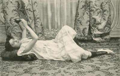 Fille, allongée sur le sol, tenant une balle au-dessus de sa tête - French Photographer