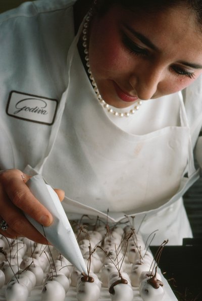 Un chef Godiva attache des tiges en chocolat à des cerises recouvertes de fondant. Bruxelles, Belgique. - James L Stanfield