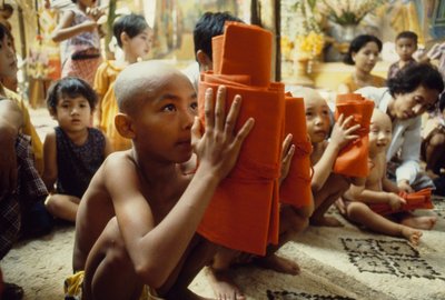 Un jeune garçon à la tête rasée reçoit ses vêtements de moine. Mandalay, Birmanie - James L Stanfield