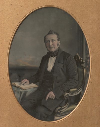 Homme assis pointant un passage dans un livre ouvert - John Jabez Edwin Mayall