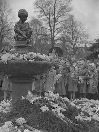 Enfants plaçant des bouquets de jonquilles sur une fontaine surmontée d