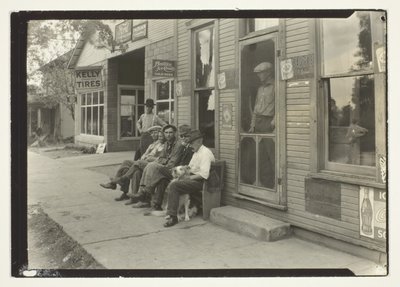 Hommes avec chien assis sur un banc devant un magasin général - Lewis Wickes Hine