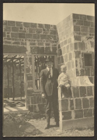 [Homme debout avec un enfant dans une maison en construction] - Louis Fleckenstein