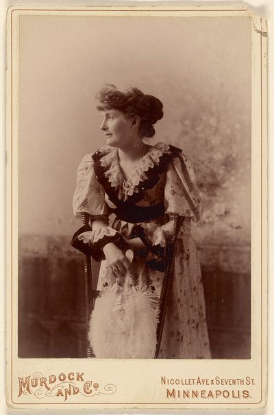 [Femme non identifiée de profil, appuyée sur une chaise, tenant un éventail de plumes]. - Murdock and Company