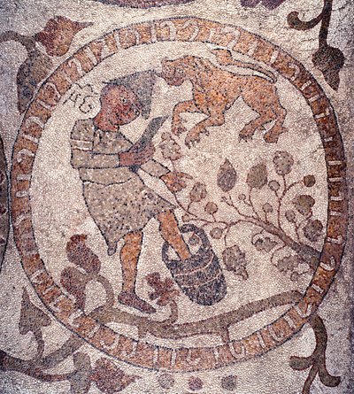 Août : un paysan portant un bonnet phrygien cueille les raisins et les écrase dans un seau. Le signe du lion est représentatif. Mosaïque de Pantaleone, prêtre et mosaïste. 1163-1166. Nef centrale de la Cathédrale d