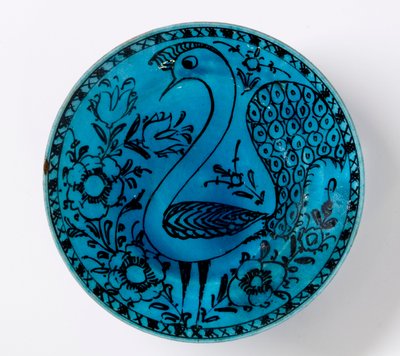 Un plat en poterie persane du 19ème siècle représentant un paon sur un fond turquoise - Persian School