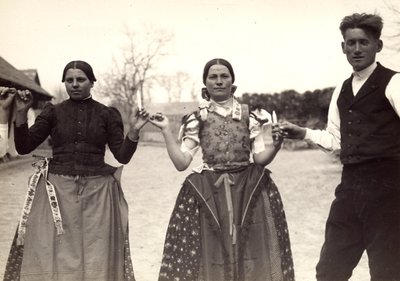 Deux dames et un homme, en costumes traditionnels hongrois, se tenant par la main dans une danse, tenant des bougies - Rudolf Balogh