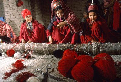 Femmes tisserandes turkmènes coupant les nœuds dans la chaîne d