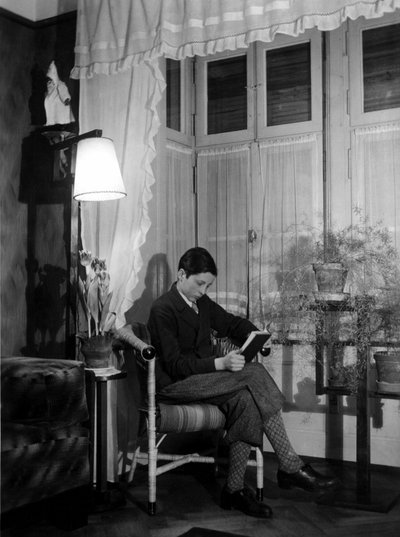 Un adolescent assis dans un intérieur bourgeois lit un livre, porte un short et des chaussettes hautes. 1915. Photo historique, femme lisant, vers 1915. - Unbekannter Künstler
