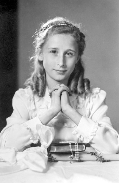 Jeune fille chrétienne avec les mains jointes en position de prière avec bible, chapelet et bougie (photo de communion). Photographie vers 1932 - Unbekannt