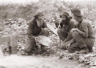 3 hommes filtrant la terre pour obtenir de l