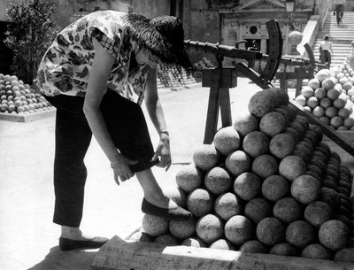 Une femme ajuste le revers de son pantalon en posant son pied sur une pile de boulets de canon dans l