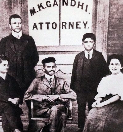 Mahatma Gandhi assis avec quatre associés devant son bureau d