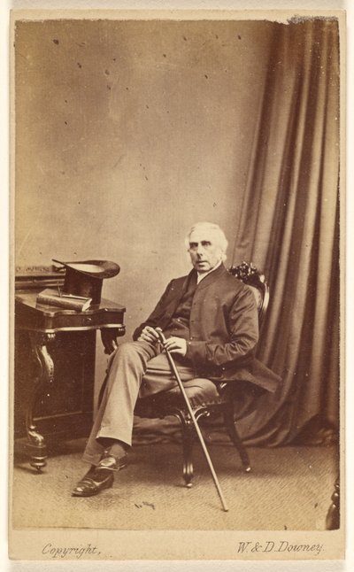 [Homme non identifié aux cheveux blancs, assis, tenant une canne, un chapeau haut de forme et un livre sur la table à gauche]. - W. and D. Downey