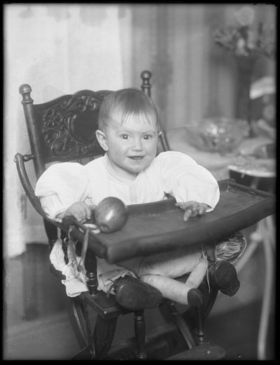 Nourrisson non identifié assis dans une chaise haute - William Davis Hassler