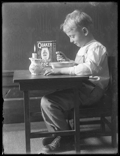 William Gray Hassler assis à une petite table mangeant un bol de céréales Quaker soufflées, vers 1912 - William Davis Hassler