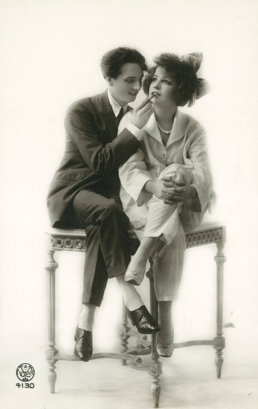 Homme androgyne en costume appliquant du rouge à lèvres à une fille en pyjama - French Photographer