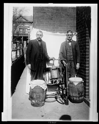 Deux hommes posant avec un alambic à whisky