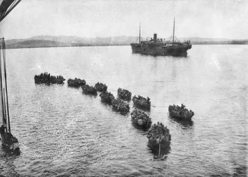 Troupes australiennes remorquées à terre dans des chalands pour débarquer à Anzac Cove, Gallipoli. En arrière-plan, le navire de transport, 1915