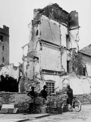 Les bombardements de Sermide. Trois personnes devant un groupe de maisons bombardées