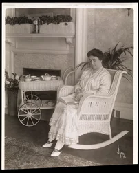 Mme Howard assise avec un livre dans un fauteuil à bascule chez elle au 200, 5e Avenue, New York, 1915-6