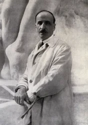 Portrait en trois-quarts du sculpteur Edoardo Rubino avec un marteau à la main. En arrière-plan, une sculpture peut être distinguée