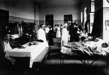 Salon décoré dans un hôpital avec des blessés de guerre, des médecins, des infirmières de la Croix-Rouge et des visiteurs