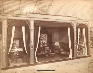 Exposition de James Shoolbred & Co. -- Bâtiment principal, Trois pièces avec meubles. La pièce de gauche contient trois armoires et une cuvette, un broc et un miroir ; la pièce centrale contient une table, des chaises, un canapé et un buffet avec un miroir