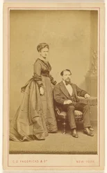 [Couple non identifié : femme debout, homme à la barbe de Vandyke assis].