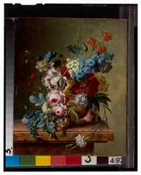 Un vase de fleurs sur une corniche en marbre et un panier de fleurs avec un chardonneret