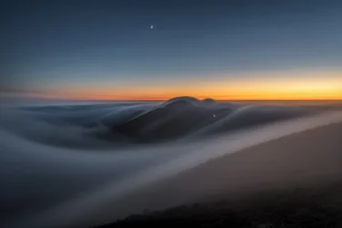 Les montagnes au crépuscule, au-dessus des nuages
