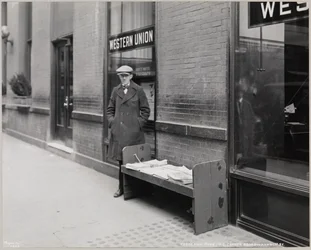 Le marchand de journaux aveugle, Frederick Rode, et le coin sud-est de Broadway et de la 41e Rue. Une enseigne Western Union est visible dans la fenêtre derrière M. Rode