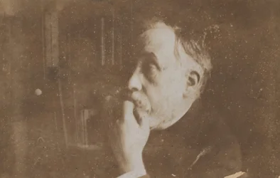 Autoportrait dans la bibliothèque, main au menton