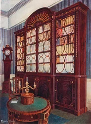 Bibliothèque en acajou incrusté. Table centrale en acajou. Horloge haute en acajou