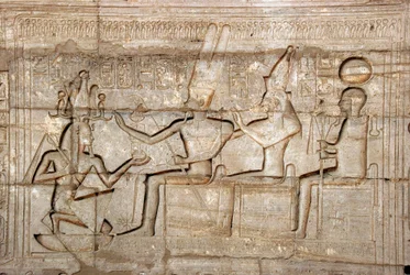 Antiquité égyptienne : relief représentant le pharaon Ramsès II devant les divinités de la triade thébaine, Amon, Mout et Khonsou ; Temple funéraire dédié au pharaon Ramsès II (1279-1213 av. J.-C.), site de Ramasseum (Ramesseum) à Louxor, Égypte.